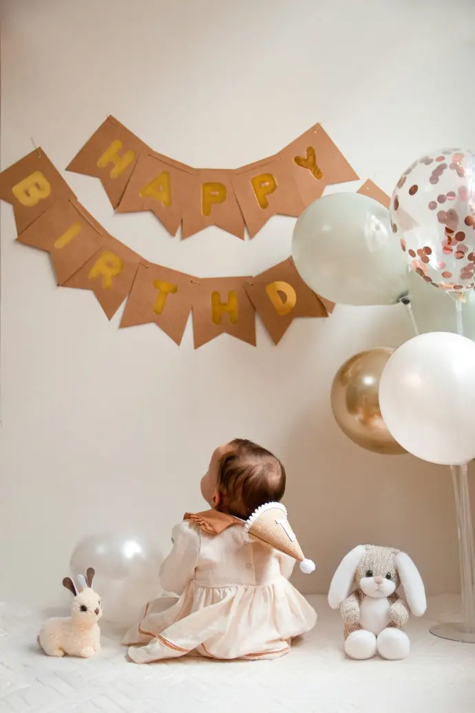 A little girl sitting in front of a birthday banner